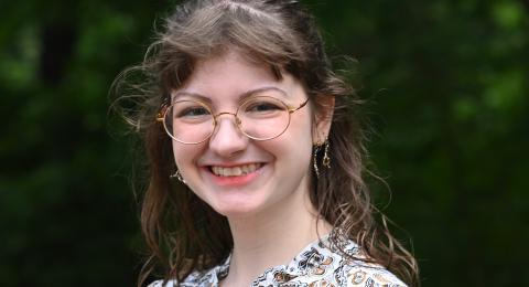 McNair scholar, professionally dressed, smiling, wooded backdrop