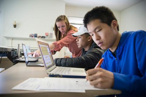 Student working on laptops with instructor support